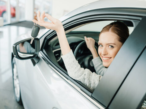 femme assise au volant, montrant sortant ses clefs de voiture par la fenêtre